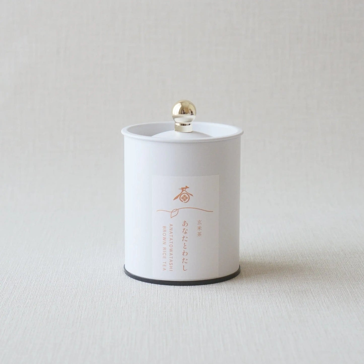 White canister of Japanese brown rice tea with gold lid and minimalist label design