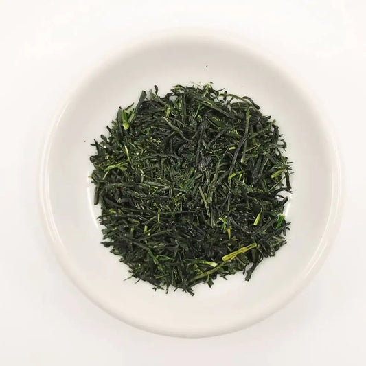 Green tea leaves on a white plate with a white background