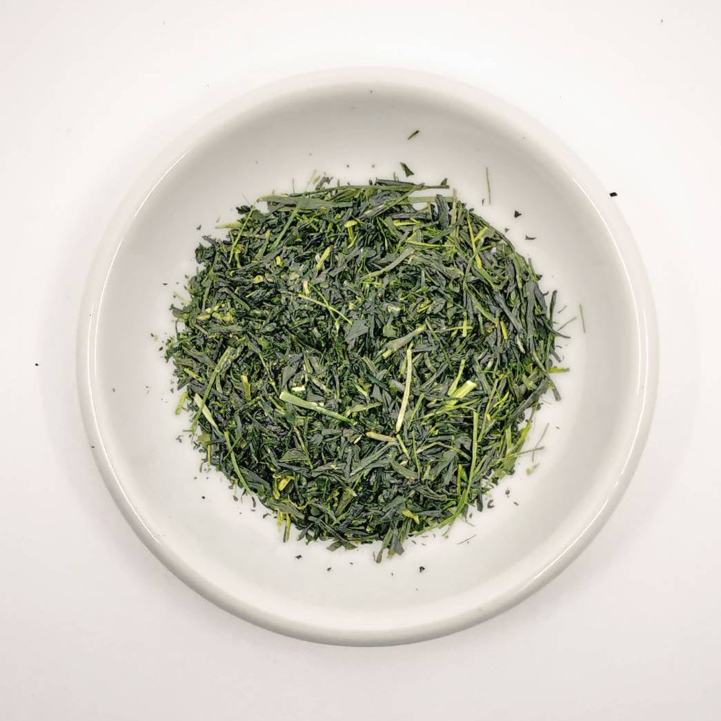 Dry green tea leaves on a white plate with a white background