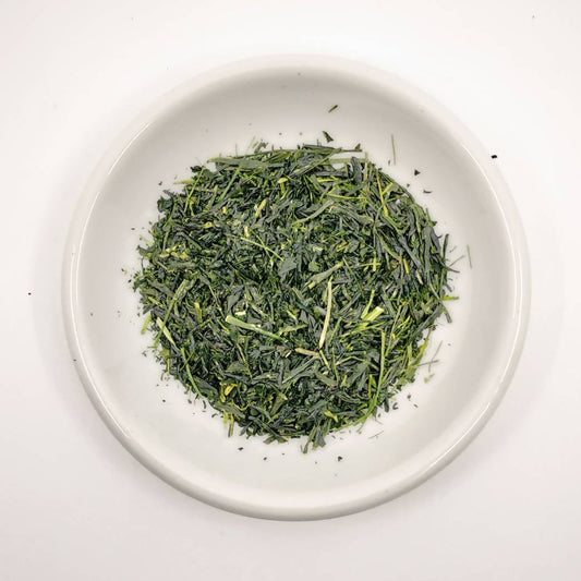 Dry green tea leaves on a white plate with a white background