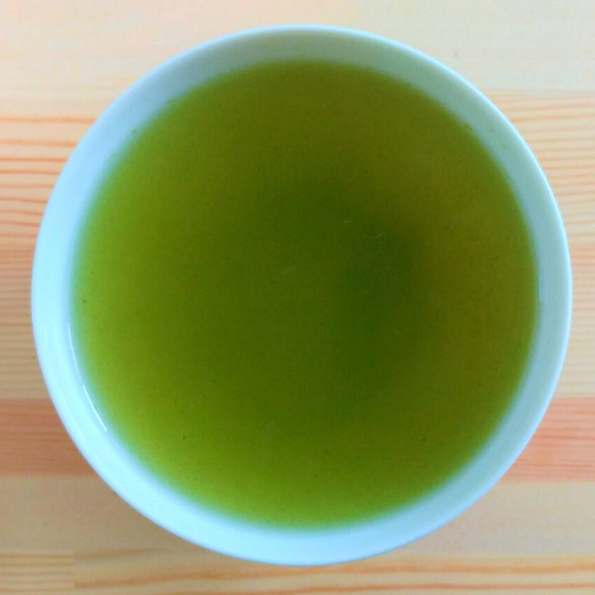 Green tea in a white cup on a striped wooden surface