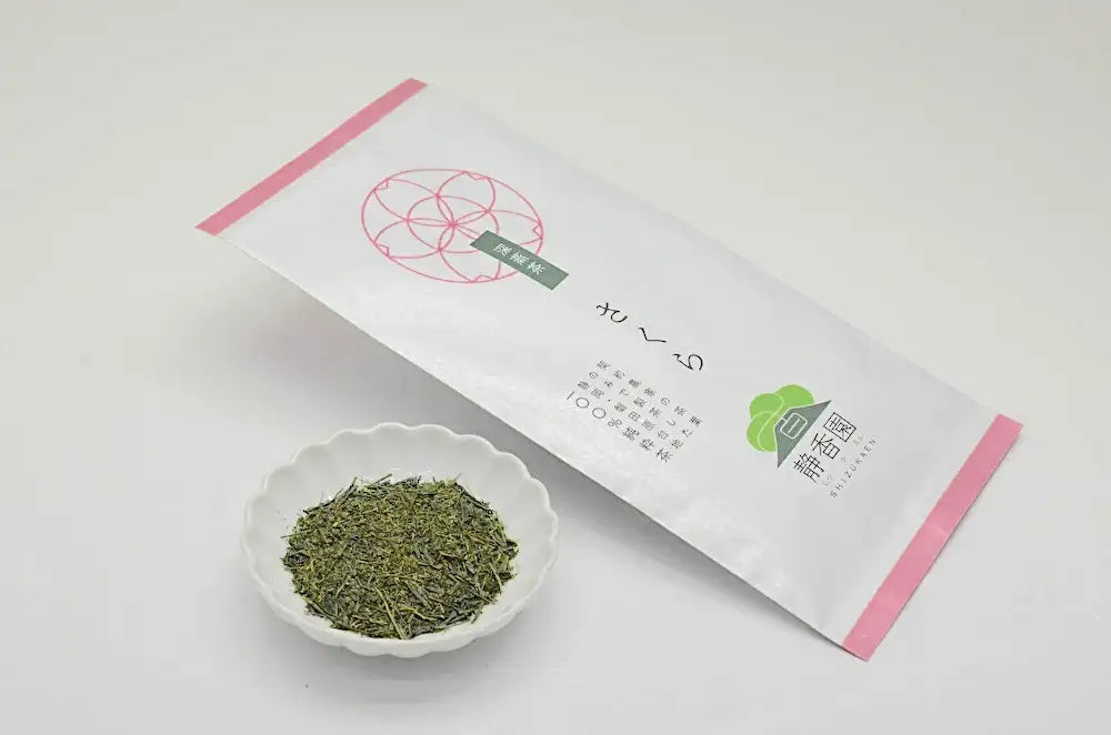 Japanese green tea leaves in white bowl beside packaged tea bag with pink accents and Japanese text