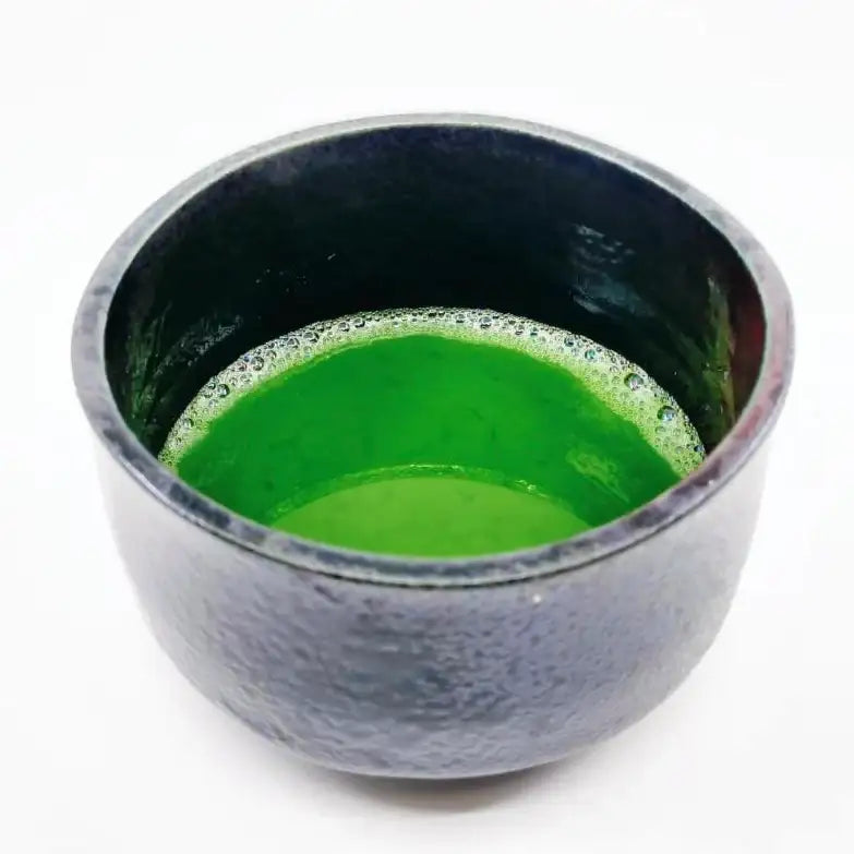 Vibrant green matcha tea in a textured ceramic bowl, showcasing authentic Japanese tea culture.