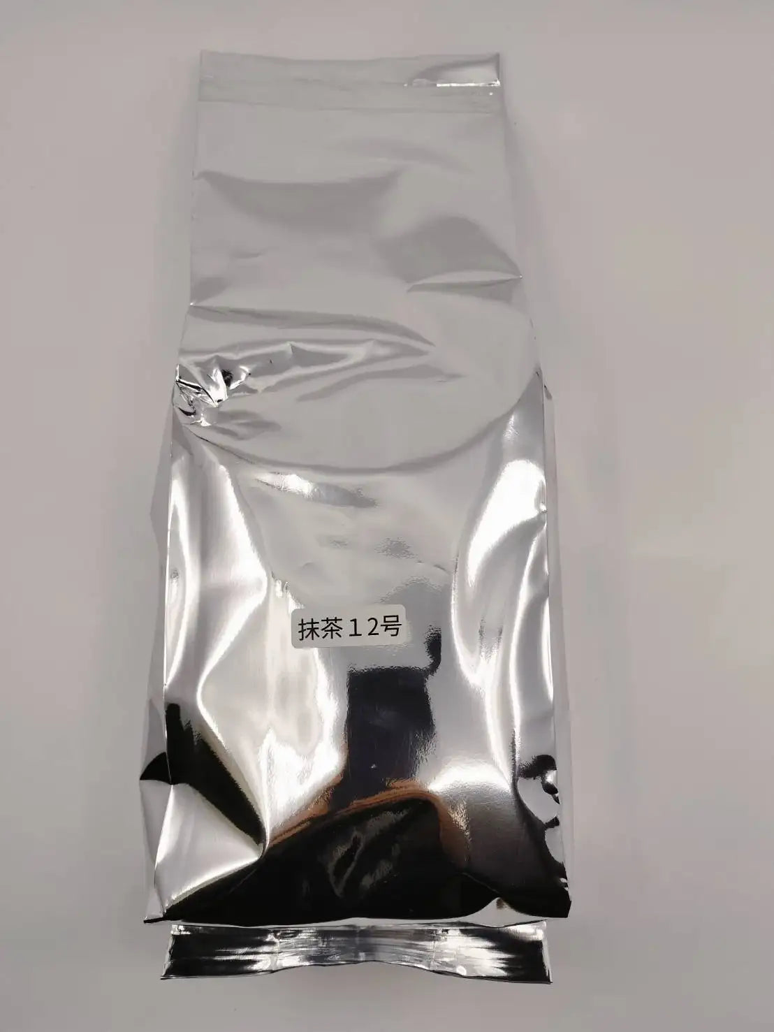 Silver bag of Japanese matcha tea labeled '抹茶12号', premium green tea powder for ceremonial use