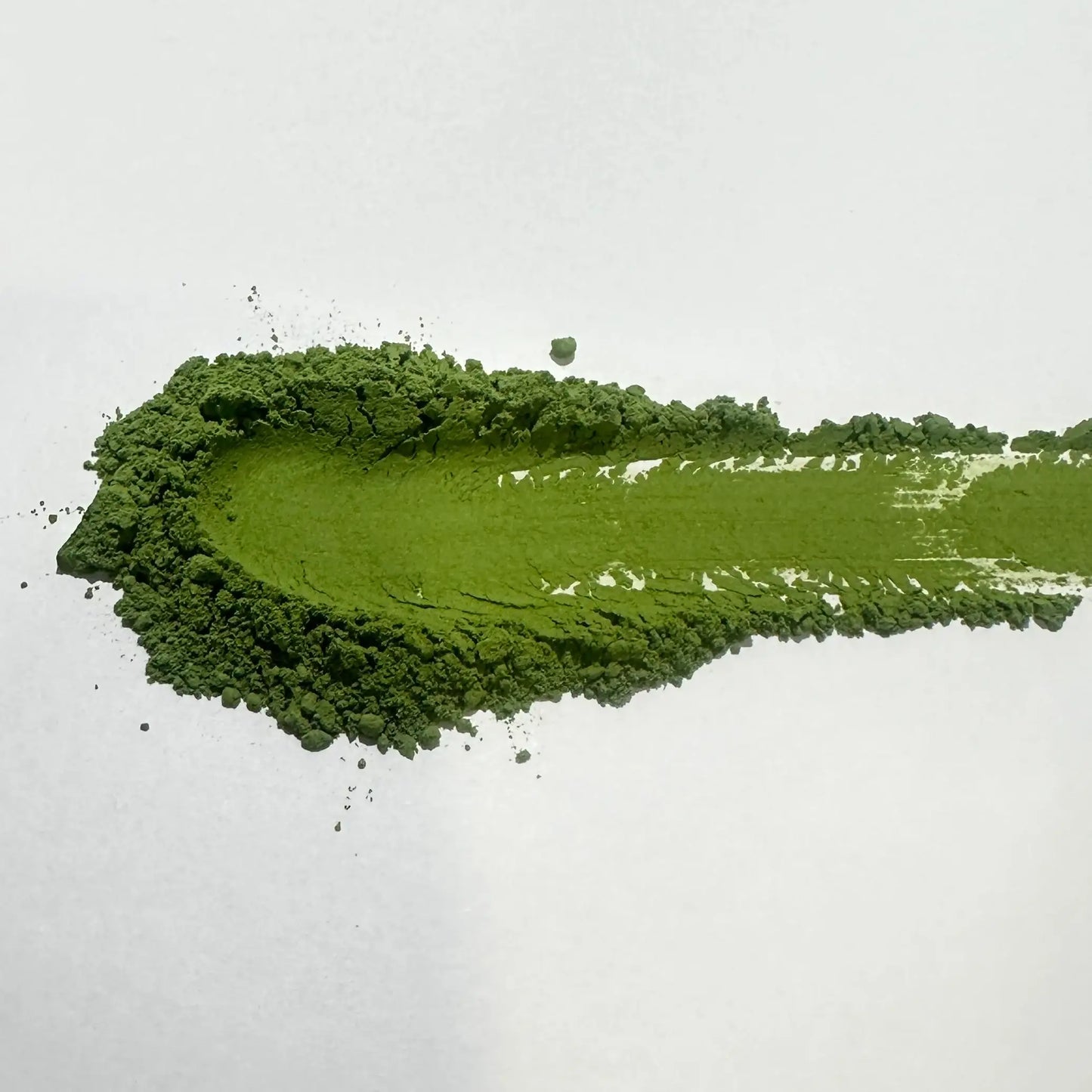 Vibrant green matcha powder swatch on white background, showcasing fine texture for Japanese tea