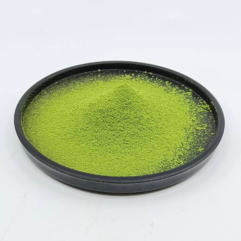 Vibrant green matcha powder in a black bowl, showcasing premium Japanese tea quality