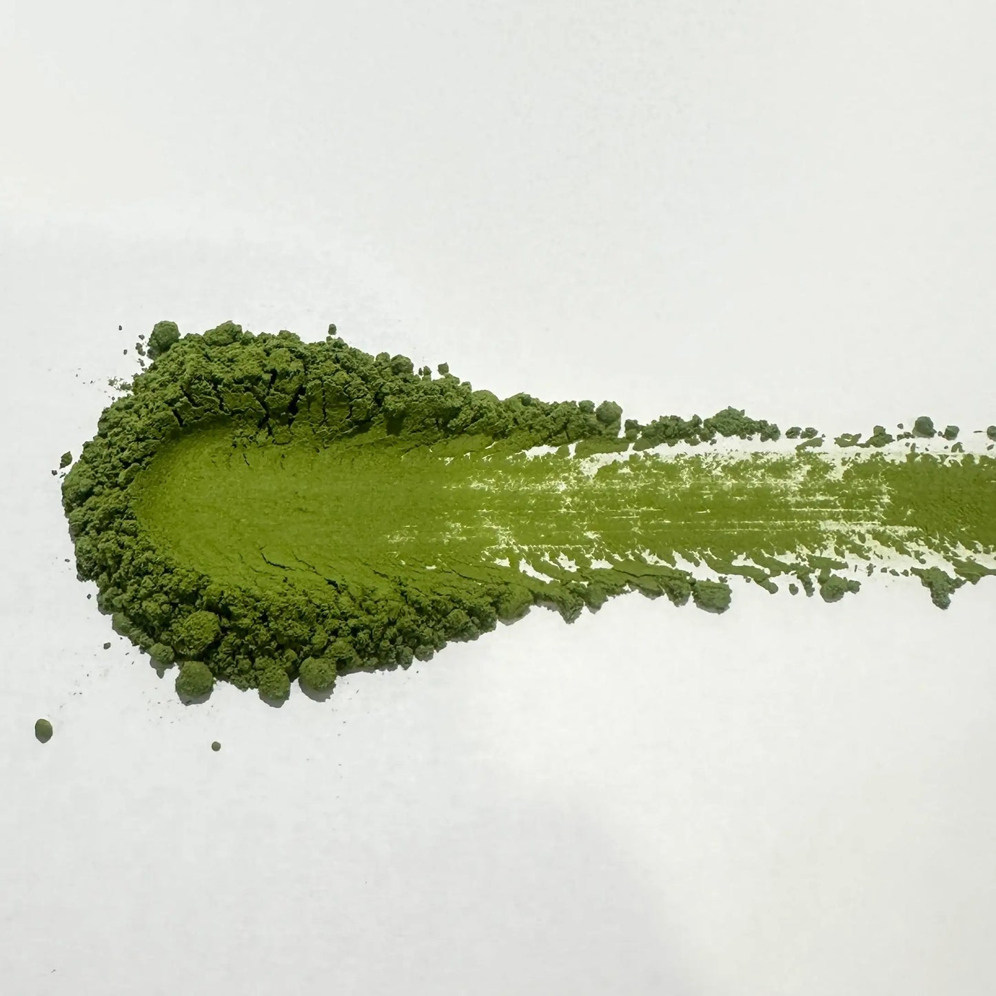 Vibrant green matcha powder swatch on white background, showcasing fine texture and rich color for Japanese tea