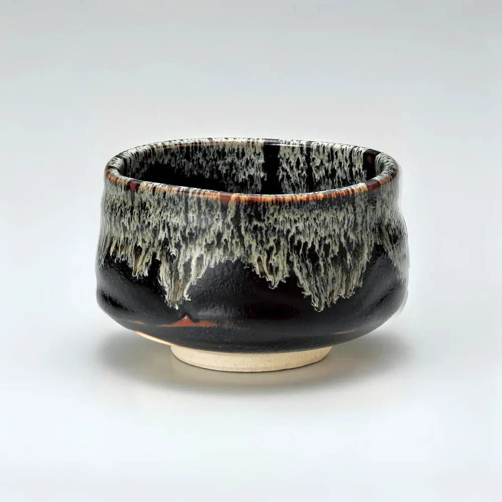 Handcrafted Japanese ceramic tea bowl with black glaze and white drip design, ideal for matcha