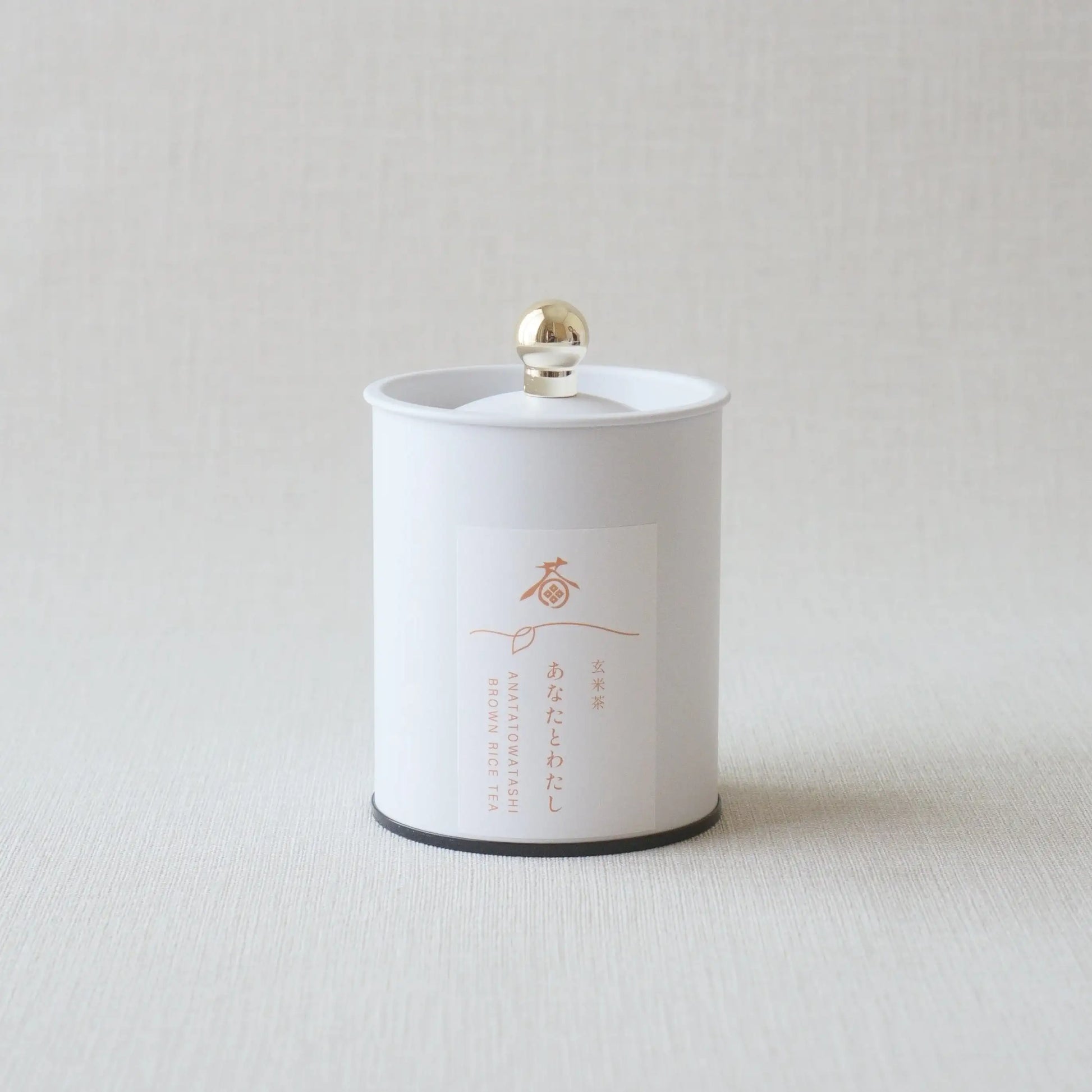 White canister of Japanese brown rice tea with gold lid and minimalist label design