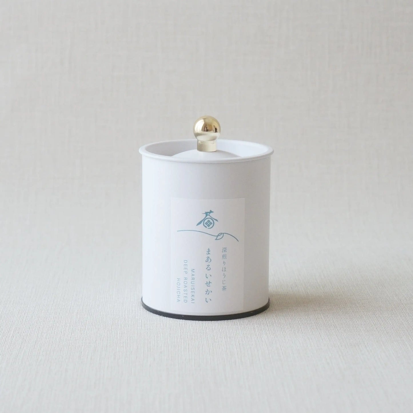 White canister of deep roasted hojicha tea with gold knob lid, minimalist design
