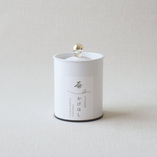 White cylindrical container with black lid on a light gray background