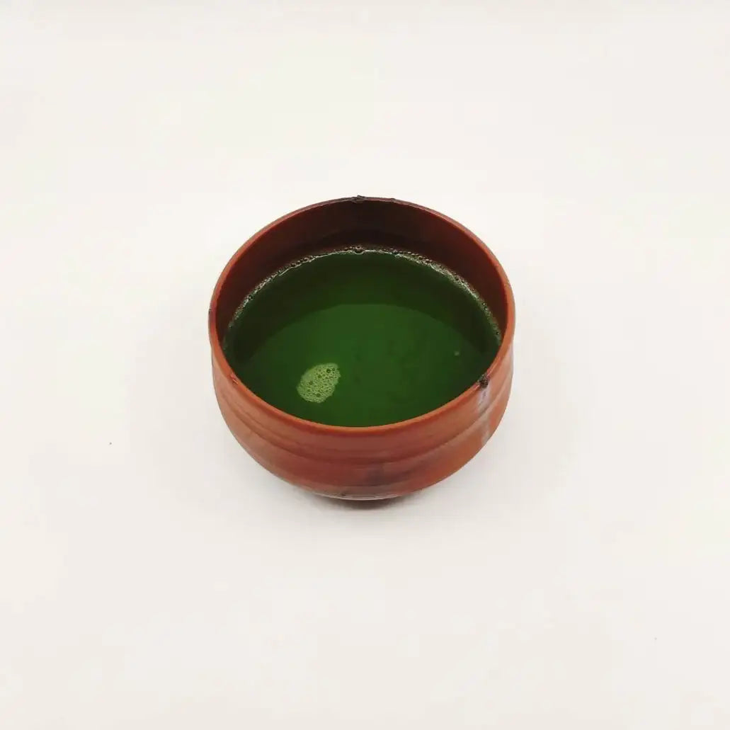 Ceramic cup with green liquid on a white background