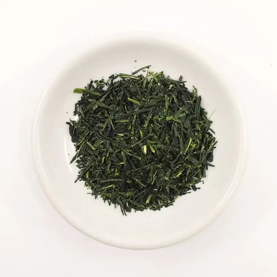 Green tea leaves in a white bowl on a white background