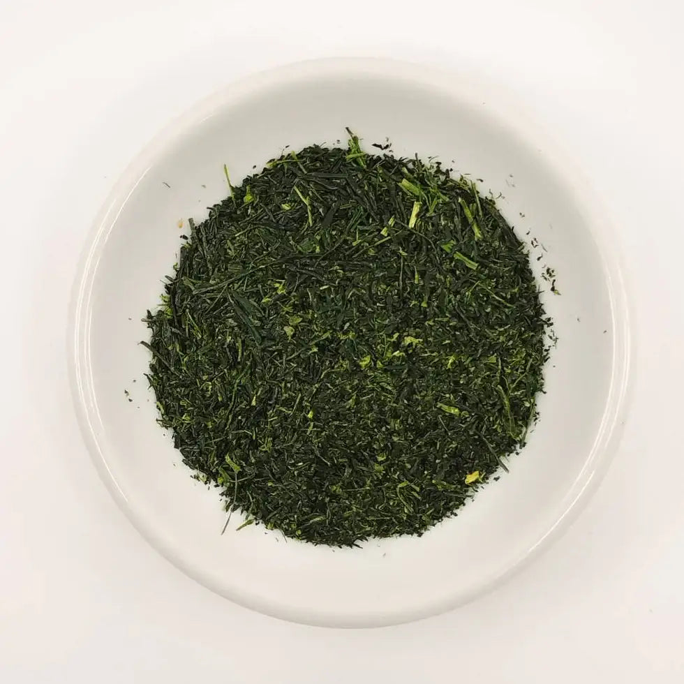 Green tea leaves in a white bowl on a white background