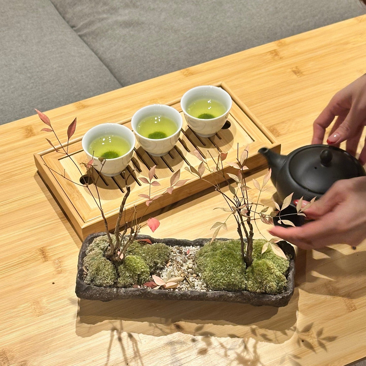 Tea ceremony setup with cups and a teapot on a wooden table.