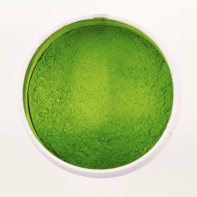 Green powder in a white bowl on a white background