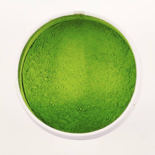 Green powder in a white bowl on a white background