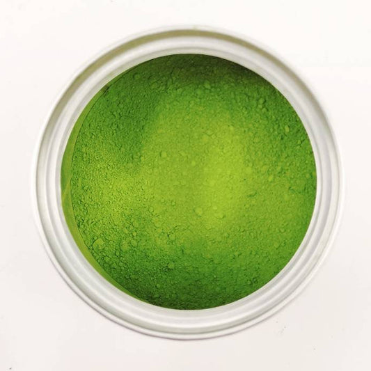 Green powder in a small white container on a white background