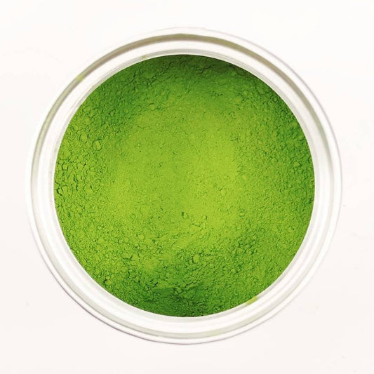 Green powder in a small transparent container on a white background