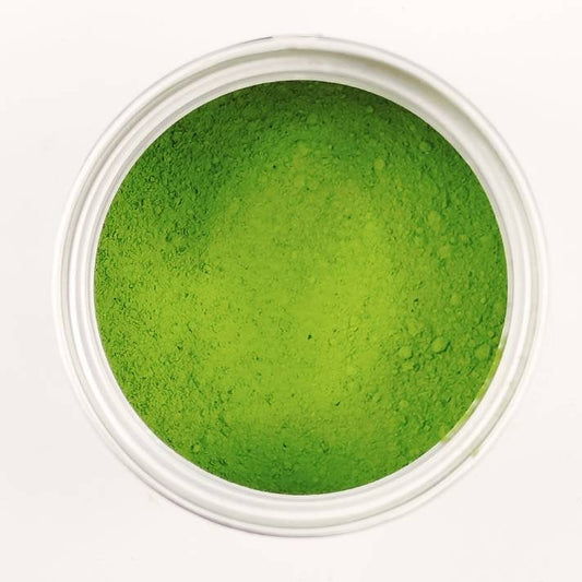 Green powder in a small white container on a white background