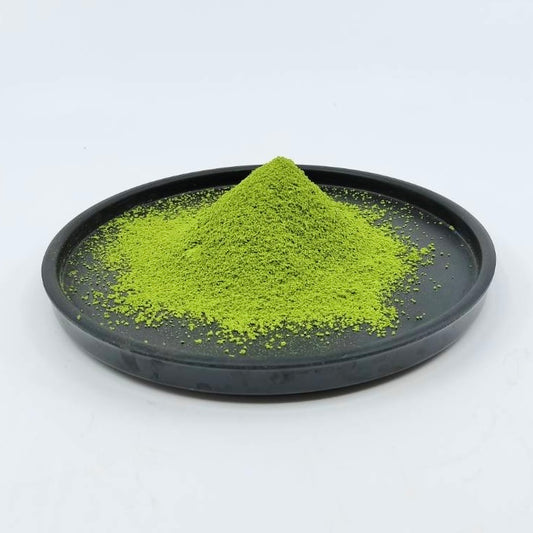 Vibrant green matcha powder mound on a black plate, premium Japanese tea product