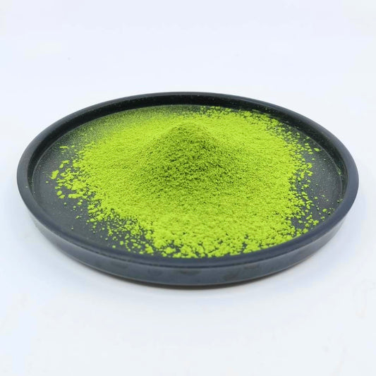 Vibrant green matcha tea powder on a black plate, premium Japanese tea.