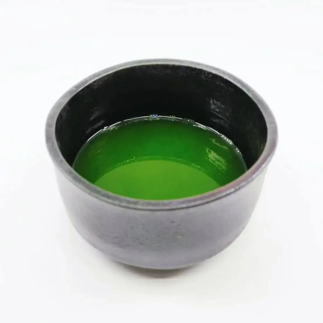 Vibrant green matcha tea in a rustic ceramic bowl, showcasing authentic Japanese tea culture.