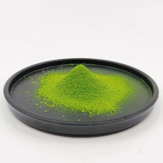 Green powder on a black tray with a white background
