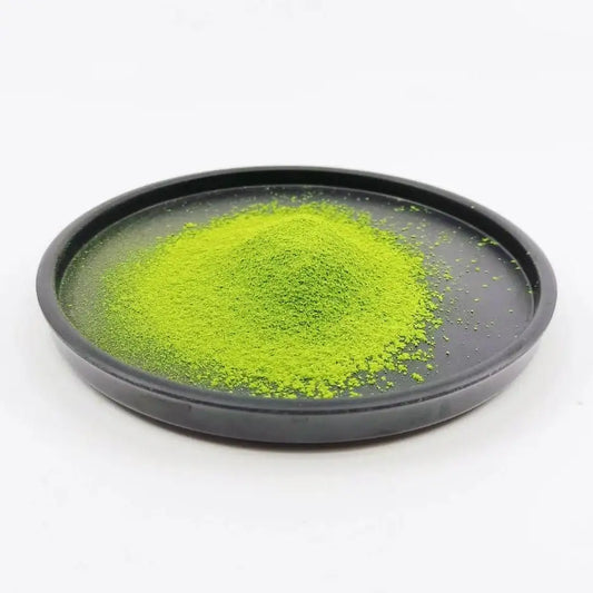 Bright green matcha powder piled on a black plate, high-quality Japanese tea.