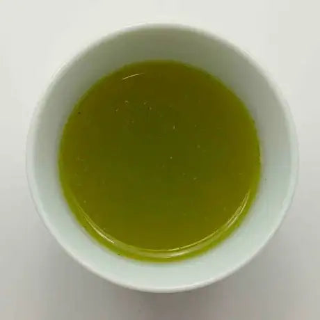 White bowl with green liquid on a white background