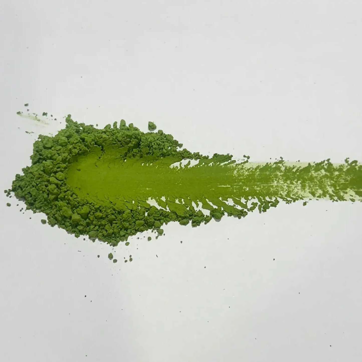 Vibrant green matcha powder swatch on white background, showcasing fine texture and rich color for Japanese tea