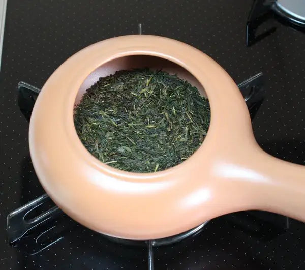 Loose leaf green tea in ceramic teapot on stovetop, ready for brewing