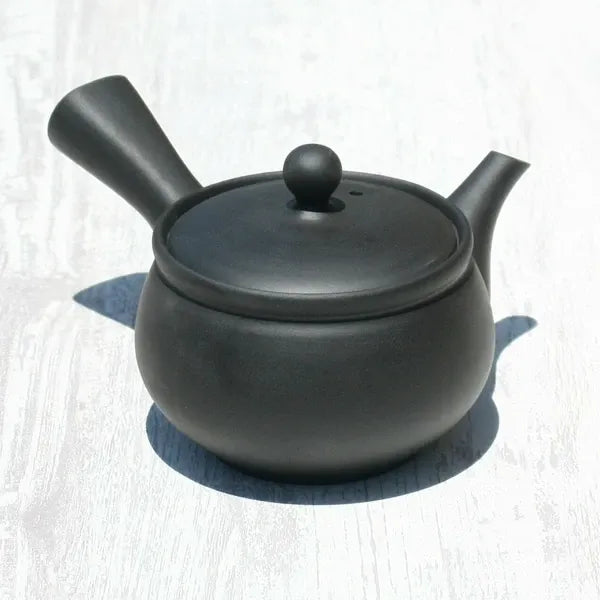 Black matte Japanese ceramic teapot with round body and side handle, ideal for loose leaf tea brewing.