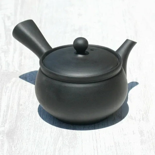 Black matte Japanese ceramic teapot with round body and side handle, ideal for loose leaf tea brewing.