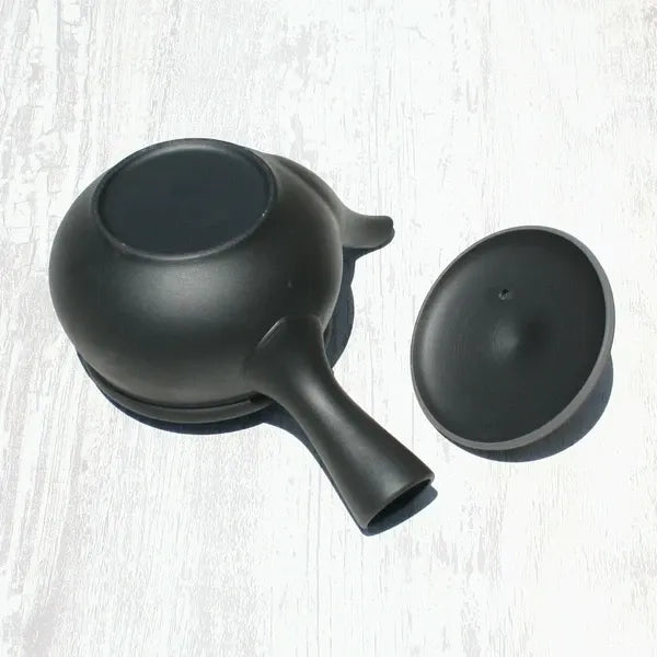 Black ceramic kyusu teapot with lid, Japanese tea ware on white wood background