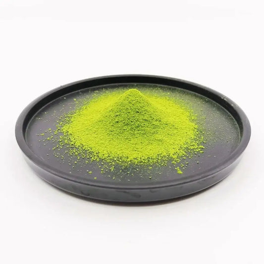 Vivid green matcha powder piled on a black dish, Japanese tea, clean white background