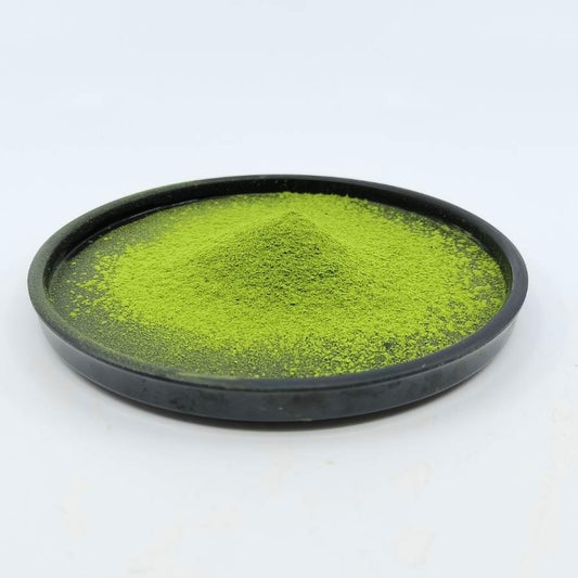 Vibrant green matcha powder on a black plate, premium Japanese tea