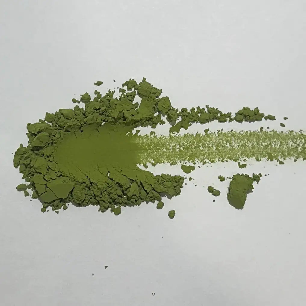Vibrant green matcha powder spread on a white surface, showcasing its fine texture and rich color.