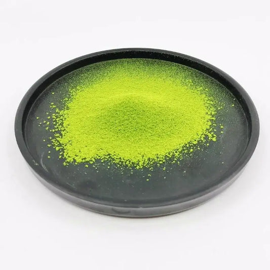 Vibrant green matcha powder on a black plate, premium Japanese tea product.