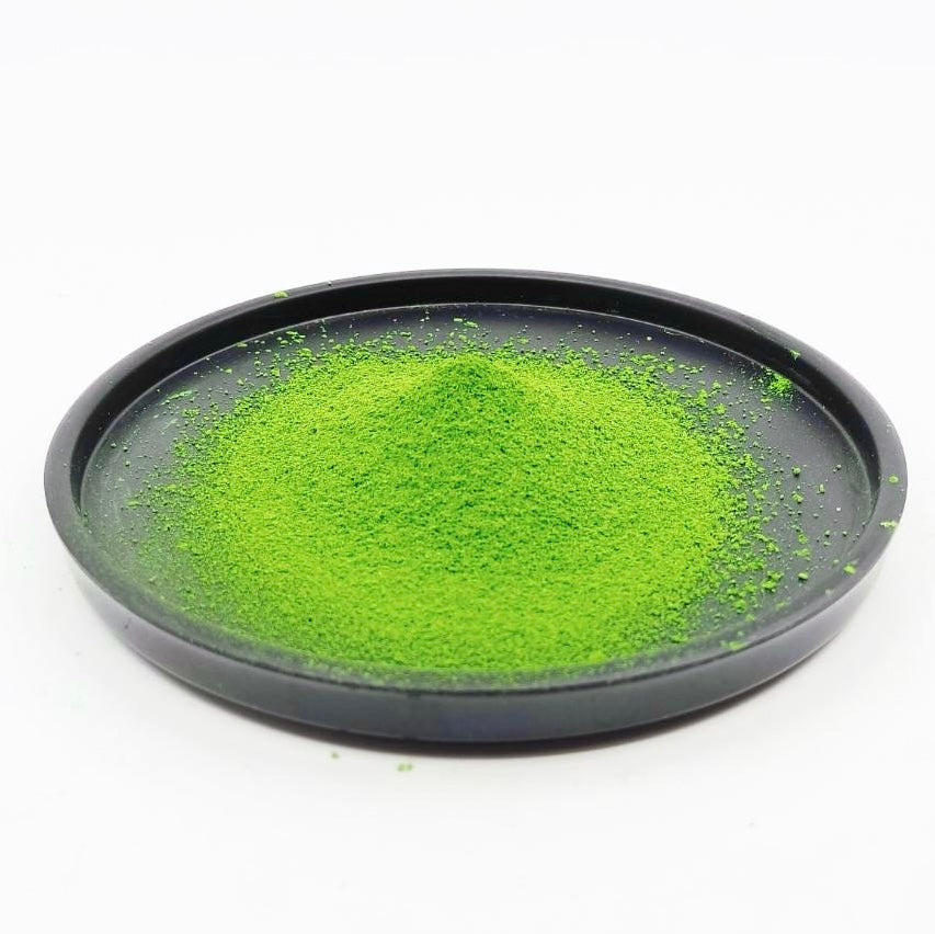 Vibrant green matcha powder in a sleek black dish, showcasing premium Japanese tea quality.
