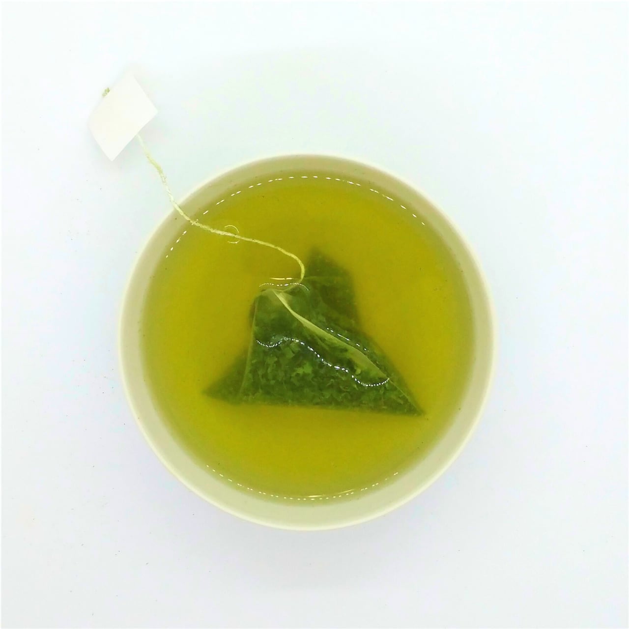 Green tea in a cup with a tea bag on a white background