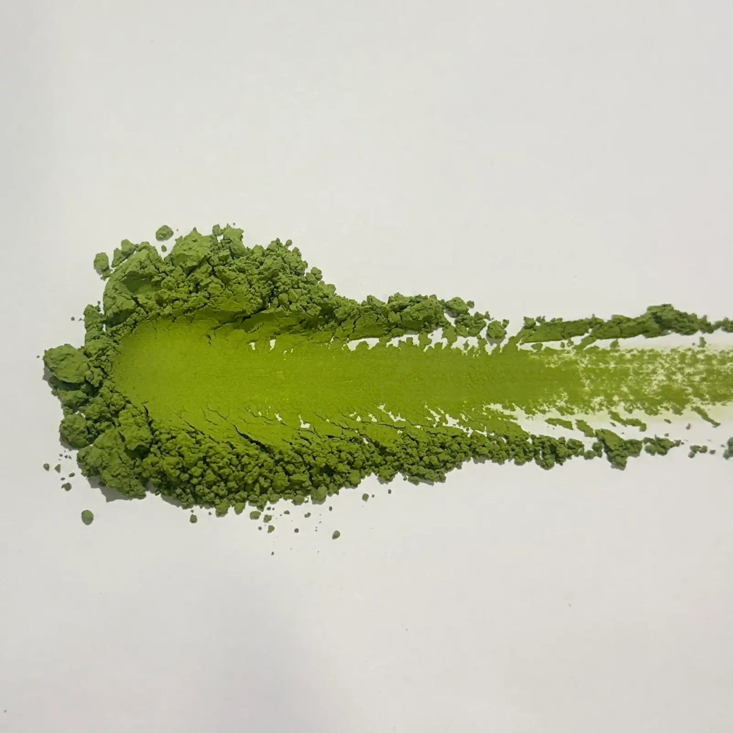 Vibrant green matcha powder swirled on white surface, showcasing fine texture for Japanese tea rituals