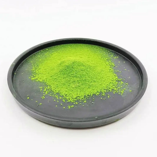 Bright green matcha powder on a black plate, Japanese tea, clean white background