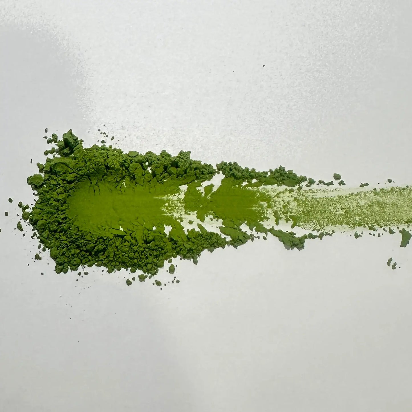 Vibrant green matcha powder swatch on white background, showcasing fine texture and rich color for Japanese tea