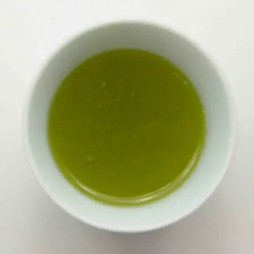 Vibrant green matcha tea in a white ceramic bowl, showcasing premium Japanese tea quality