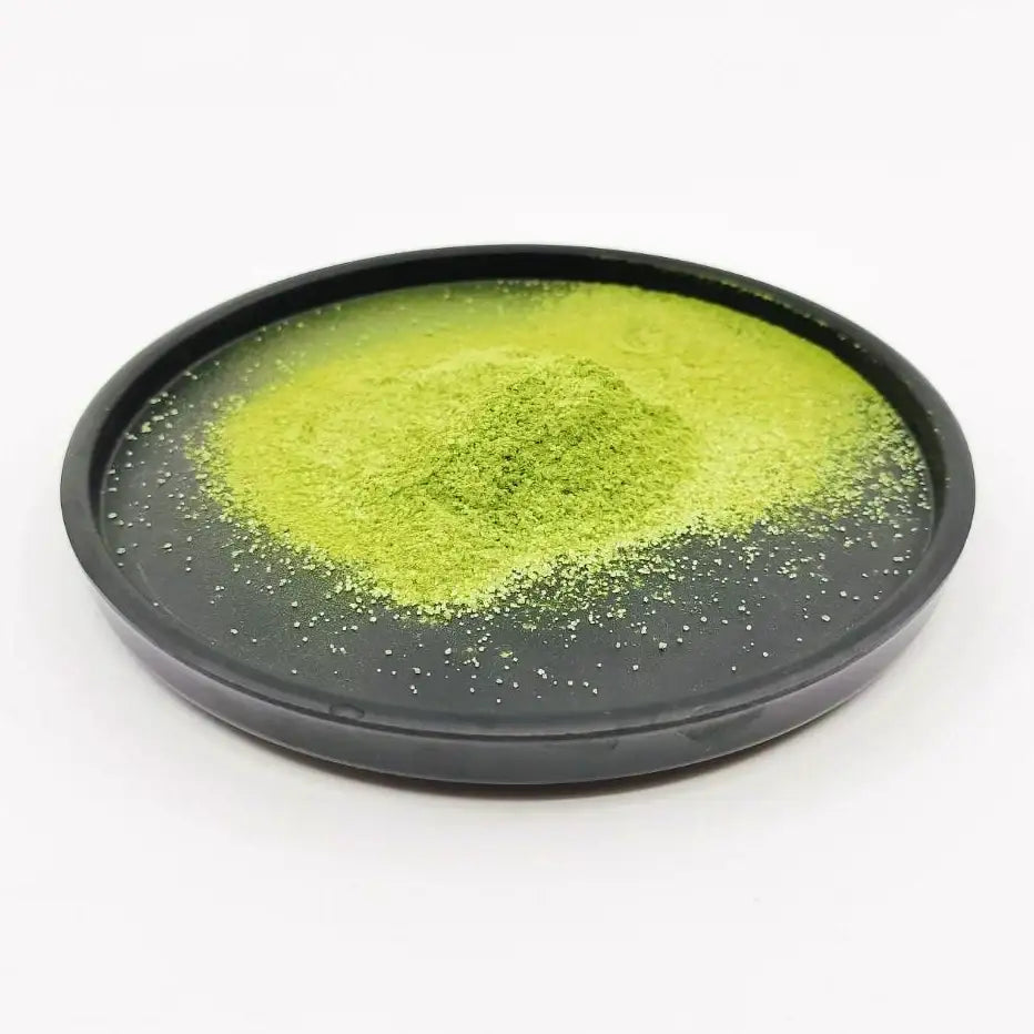 Vibrant green matcha powder on black dish, premium Japanese tea for ceremonial use