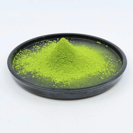 Vibrant green matcha powder mound on a black plate, Japanese tea product