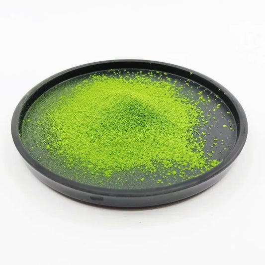 Bright green matcha tea powder on a black plate, Japanese tea product