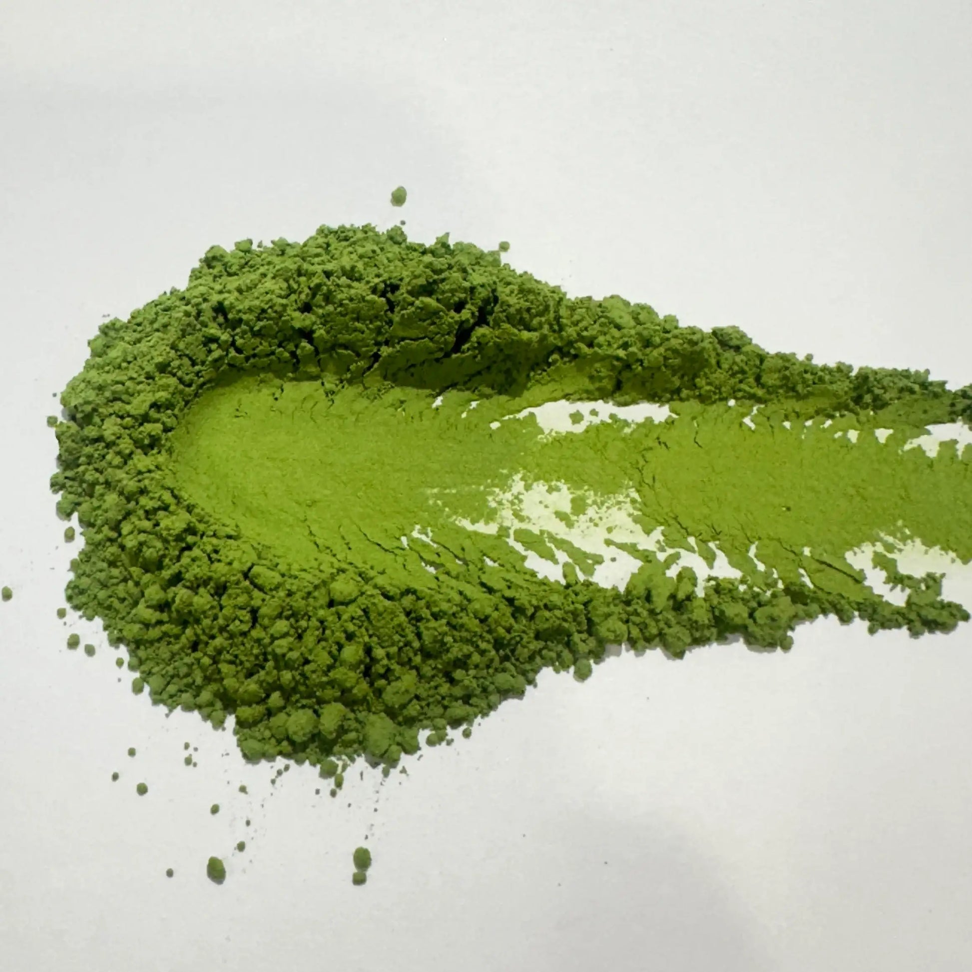 Vibrant green matcha powder pile on white background, showcasing fine texture for Japanese tea