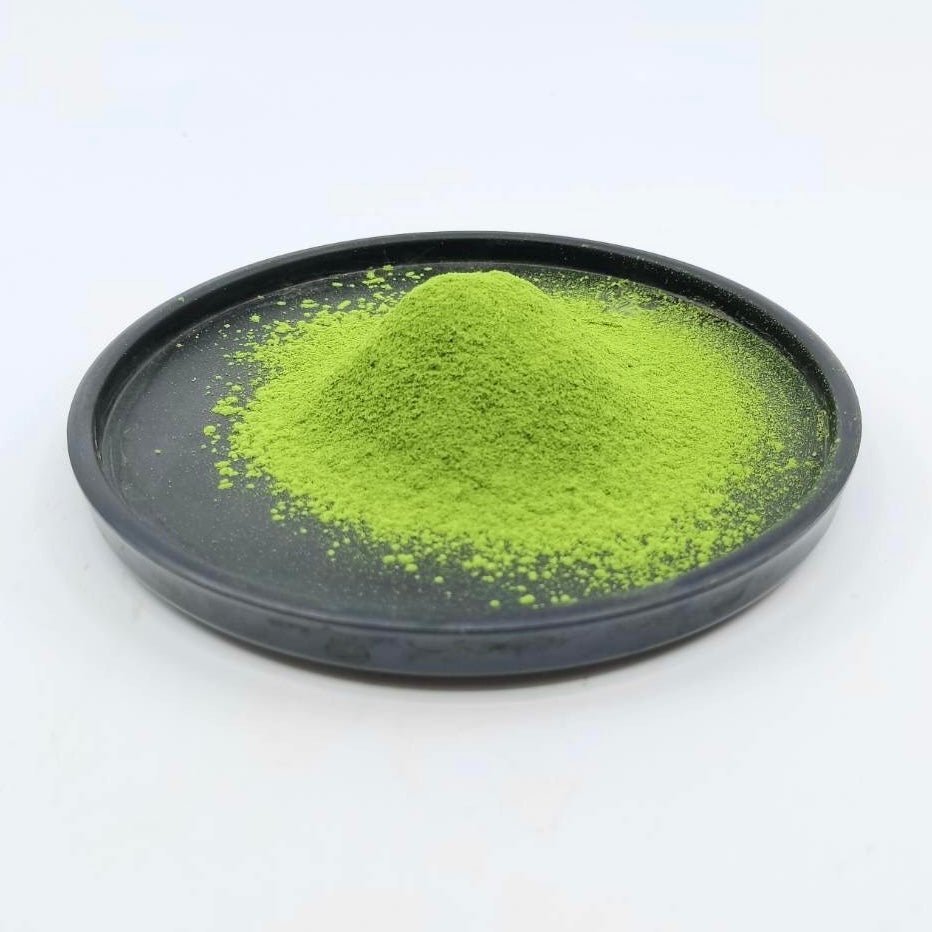 Vibrant green matcha powder piled on a black dish, showcasing premium Japanese tea quality.